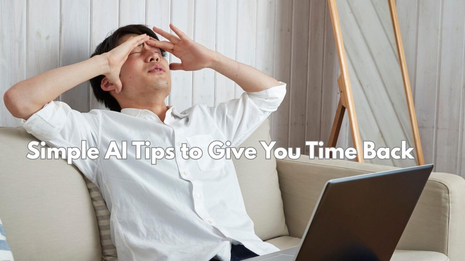 A picture of a man in a white shirt with a laptop on his lap and holding his hands to his head in frustration.
